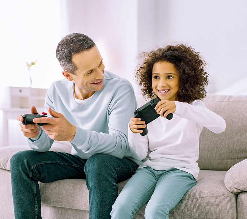 cheerful little girl playing console with dad